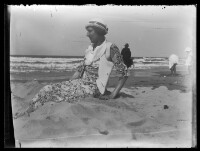 fo040051: Vrouw, in bloemenjurk, zittend op het strand