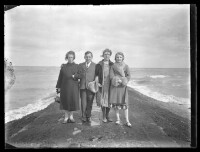 fo040043: Drie vrouwen en een man poseren op een golfbreker aan zee