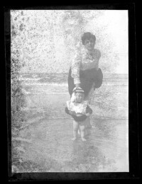 fo040040: Een vrouw en kind met hun voeten in de zee