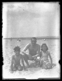 fo040212: Een man en twee kinderen, in zwemkledij, op het strand