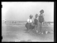 fo040139: Een man en twee kinderen poseren op het strand