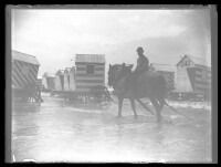 fo040226: Een man op een visserspaard met op de achtergrond strandcabines