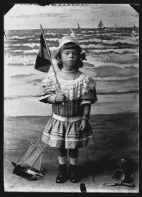 fo040082: Kind, met vlag in de hand, in een fotostudio ' aan zee'