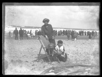 fo040093: Vrouw met twee kinderen, in strandstoel, op het strand