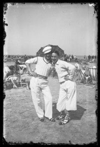 fo040097: Twee mannen poseren ludiek met parasol op het strand